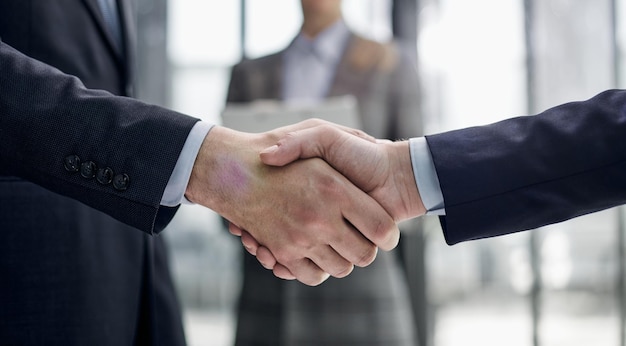 Два деловых человека пожимают друг другу руки перед своими коллегами