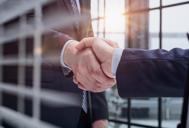 Two business people shaking hands in front of their colleagues