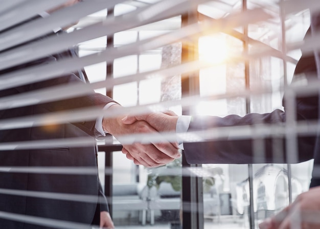 Two business people shaking hands in front of their colleagues