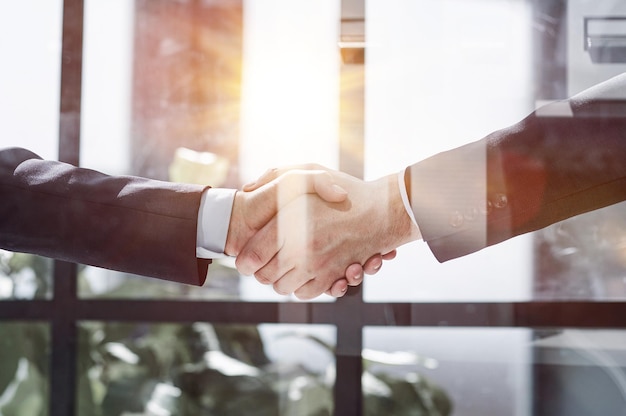 Two business people shaking hands in front of their colleagues