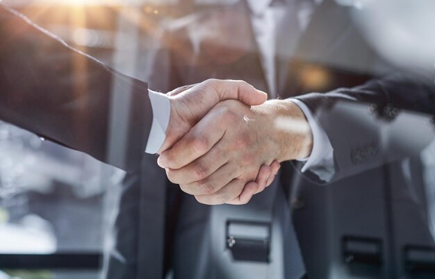 Two business people shaking hands in front of their colleagues