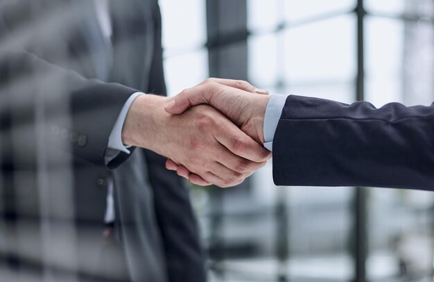 Two business people shaking hands in front of their colleagues