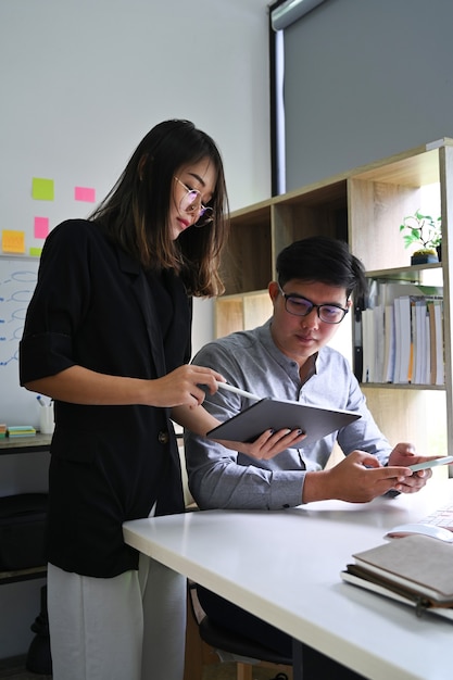 Two business people sharing ideas and discussing startup business plan in modern office.