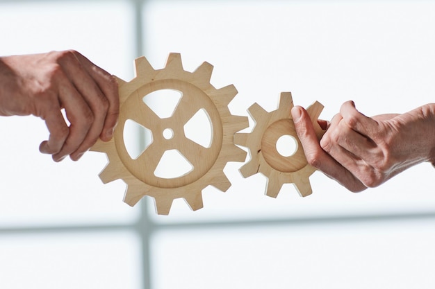 Two business people united wooden cogs gears closeup