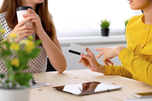 Two business woman or friends are talking and using tablet computer.