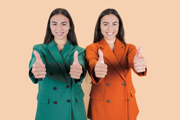 two business women hispanic say ok beige background twins