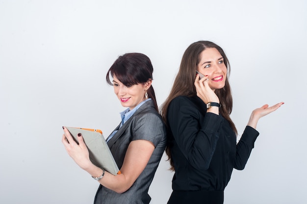 Two business women standing backs to each other and smile