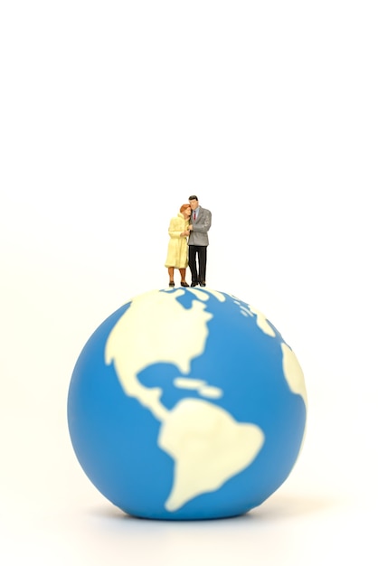 Two businessman and businesswoman miniature figure people walking and standing on mini world ball