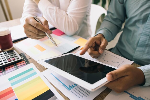 Two businessmen are working analyzing the company annual budget and using digital tablet to find information data result
