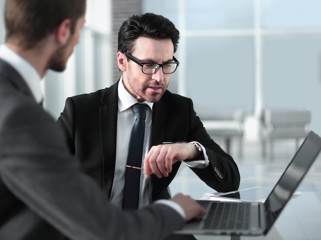 Two businessmen discussing information from a laptop