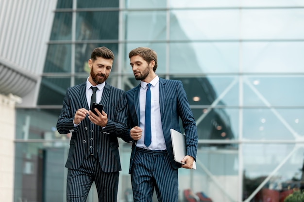 Photo two businessmen discussing together on a news on a smart phone during a business travel. business, technology and people concept.