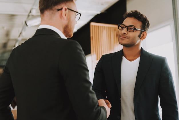 two businessmen in glasses is shaking hands
