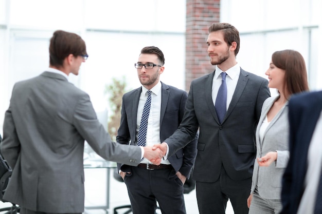 Two businessmen making agreement their female colleague standing nearby