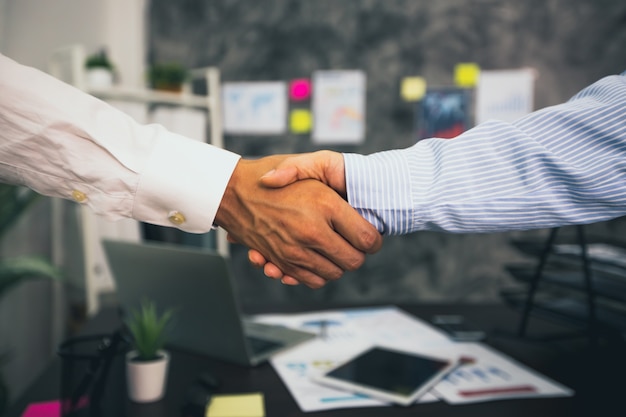 Two businessmen shakes hand at the office