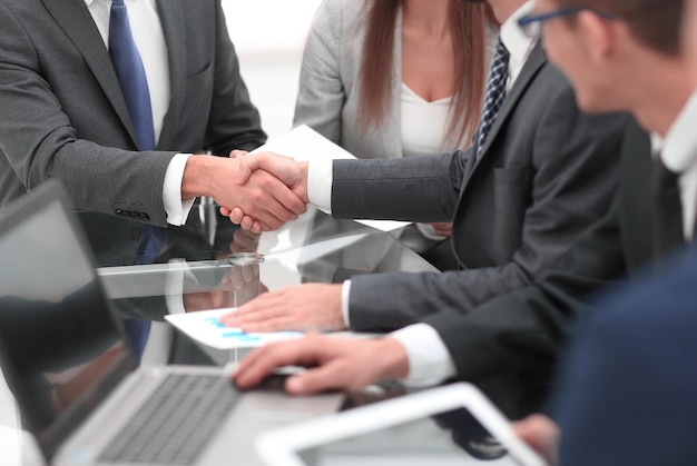 Two businessmen shaking hands with colleagues on background