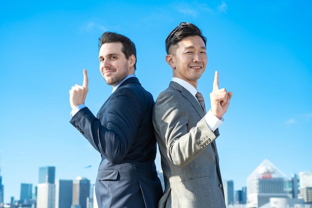 Two businessmen standing back to back on fine day