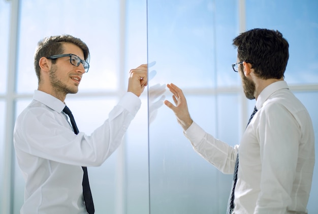 Two businessmen standing in a modern office with glass wallsbusiness concept