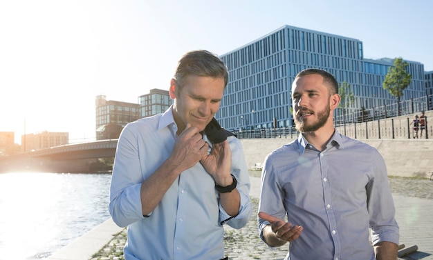 Two businessmen talking at the riverbank