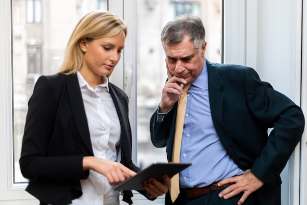 Two businesspeople discussing while looking at a tablet