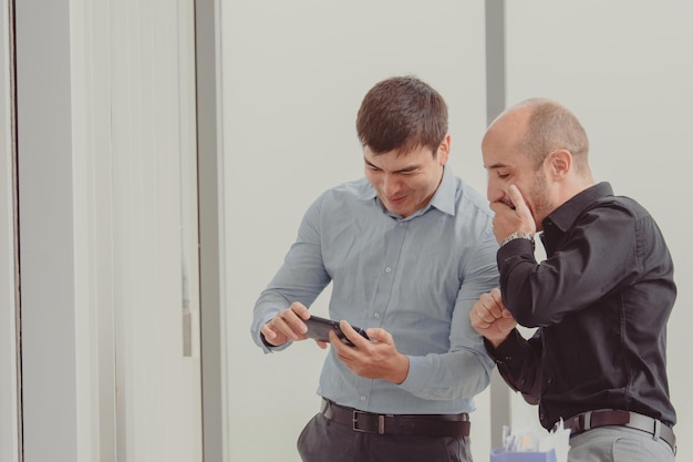 Two businesspeople looking phone trading online