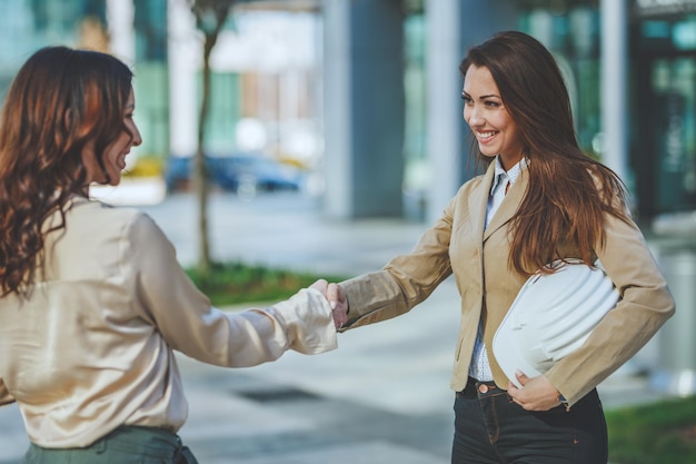 Photo two businesswomen are shaking hands with each other after good deal.