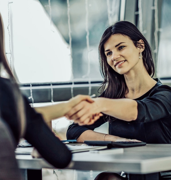 Two Businesswomen Shaking Hands In Modern Office