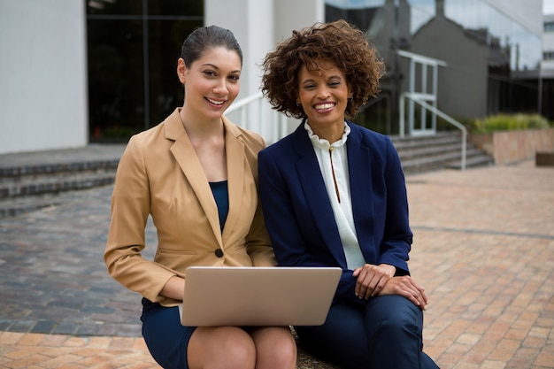 Две женщины-предприниматели, использующие ноутбук в офисных помещениях