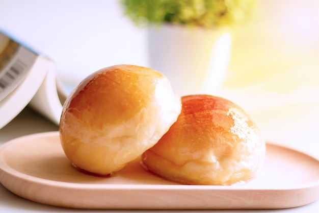 Two butter bread bun on wooden plate with book and flower in cafe shop on leisure day