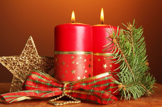 Two candles and christmas decorations, on brown background