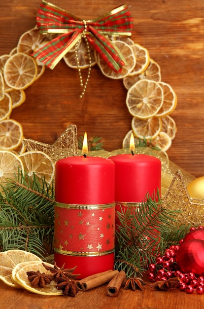 Two candles and christmas decorations, on wooden background