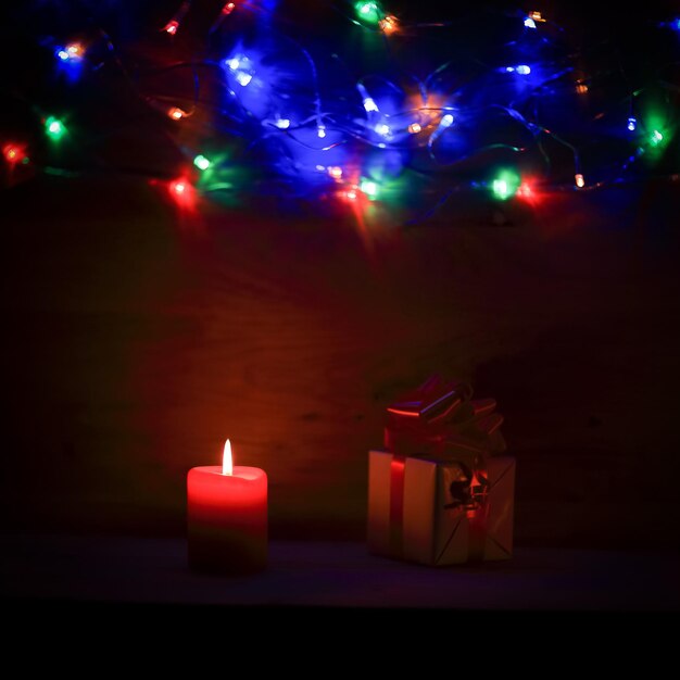 Two candles and Christmas gift on holiday background