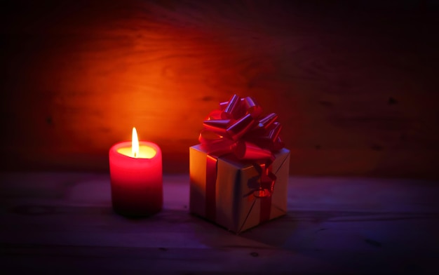 Two candles and Christmas gift on holiday background