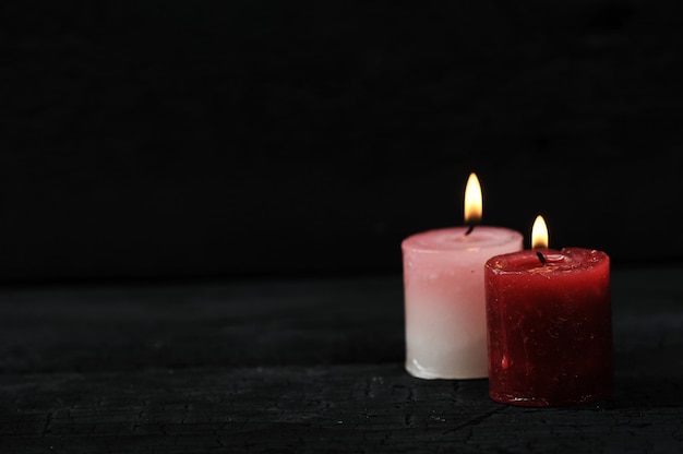 Two candles with lit fire on black background