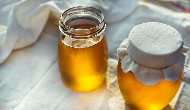 Two cans of natural honey. Honey on the fabric.