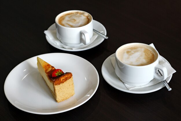 Two cappuccinos and a piece cheesecake