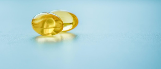 Two capsules of fish oil on a blue background