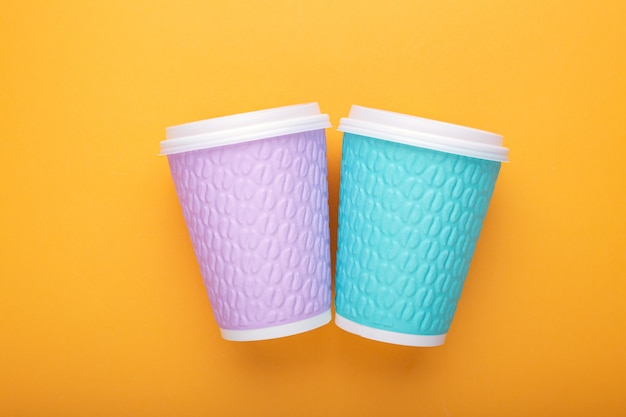Two cardboard coffee cups on a yellow background
