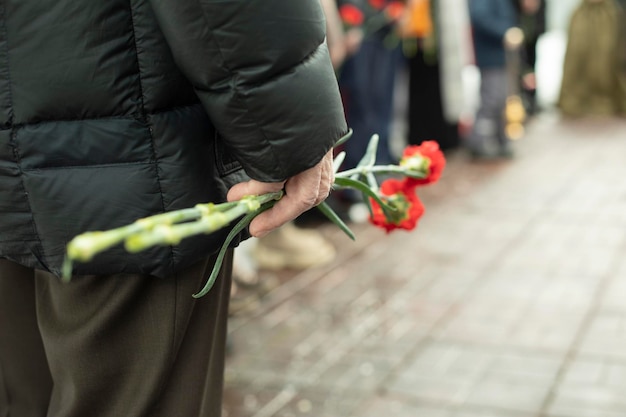 Two carnations in mans hand details of funeral ceremony commemorative flowers in hand