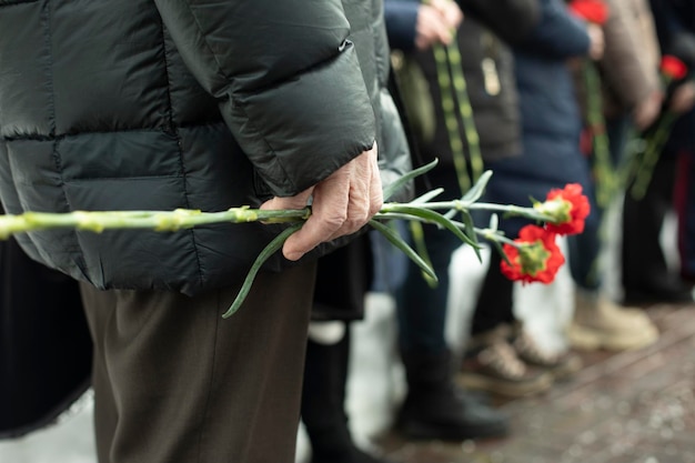 Two carnations in mans hand details of funeral ceremony commemorative flowers in hand
