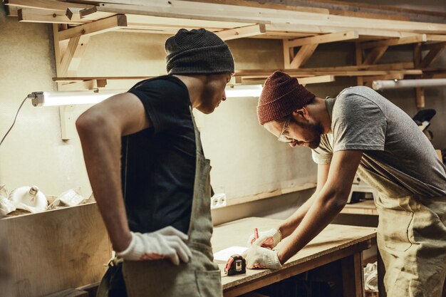 Two carpenters making sketches on workbench