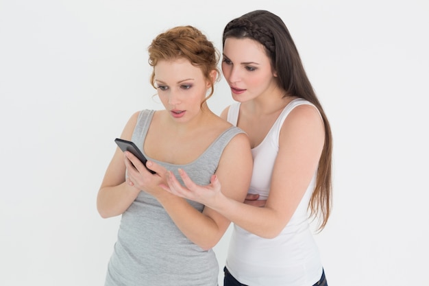Два случайных молодых женщин-друзей, глядя на мобильный телефон