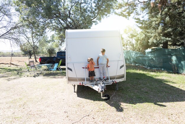 Due bambini caucasici giocano e trascorrono vacanze alternative in roulotte