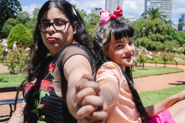 Two caucasian latin girls holding hands outside in a park sitting celebrating valentines day