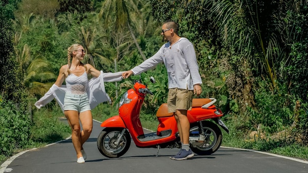 Two caucasian tourist woman man dance near scooter love couple
on red motorbike