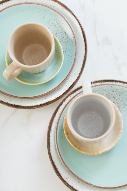 Two ceramic cups and plates on white marble table