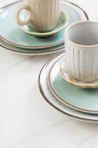 Two ceramic cups and plates on white marble table