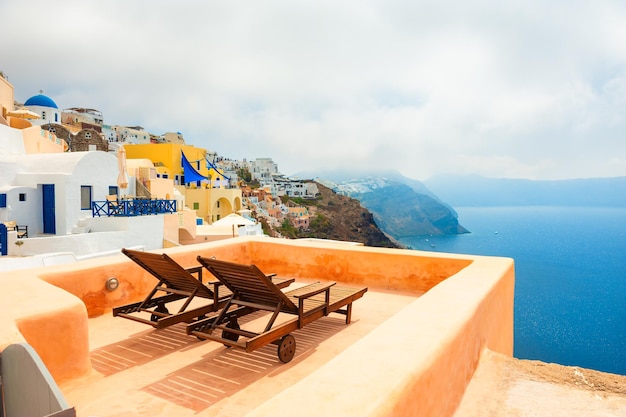 Two chaise lounges on the terrace with sea view. Misty morning on Santorini island, Greece.