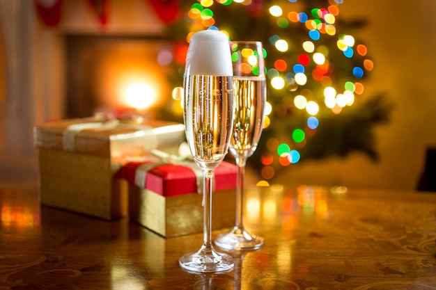 Two champagne glasses on table against fireplace decorated for Christmas