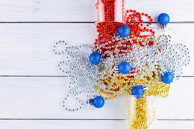 Two champagne glasses with Christmas beads on white background. Christmas balls and decorations on the boards. Top view