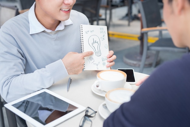 Two cheerful asian business people discussing with documents